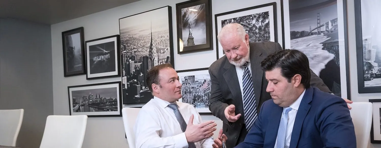 three men looking over a document at a conference room table