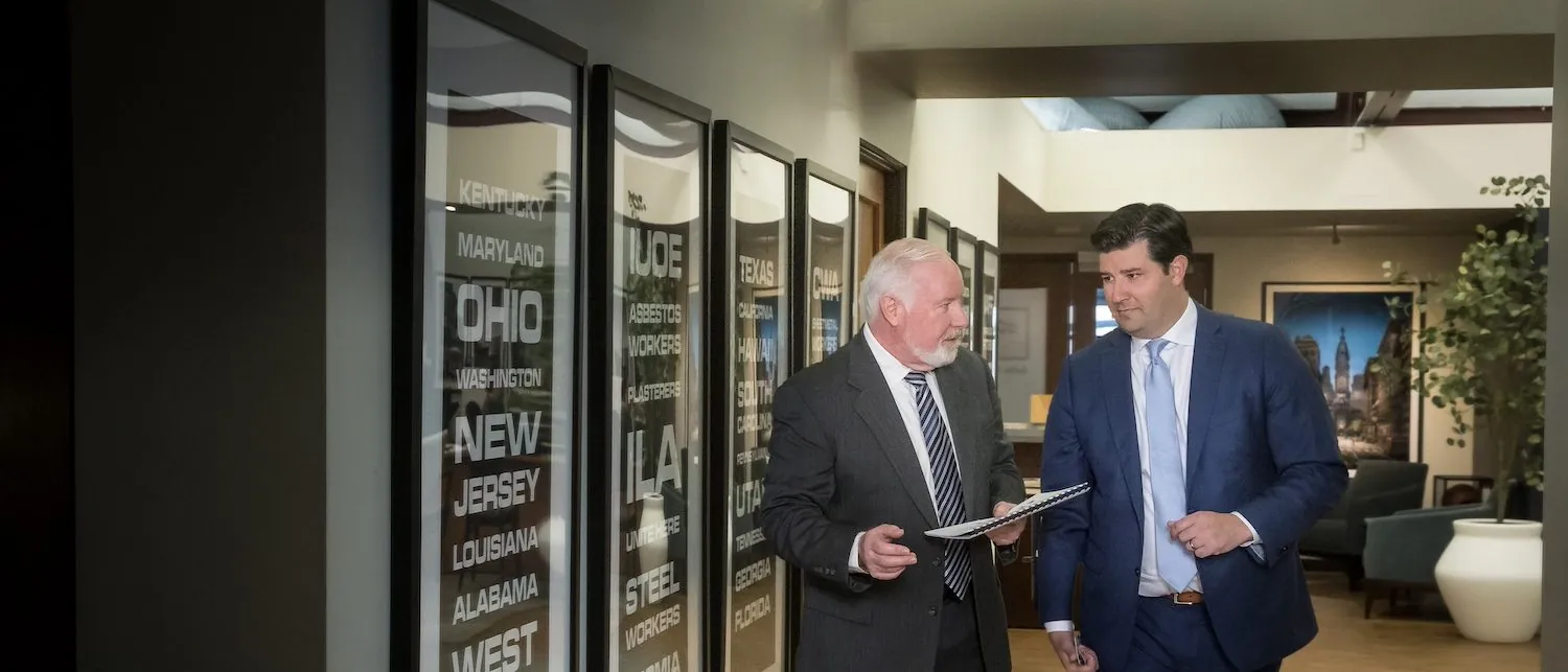 two men walking in hallway holding documents