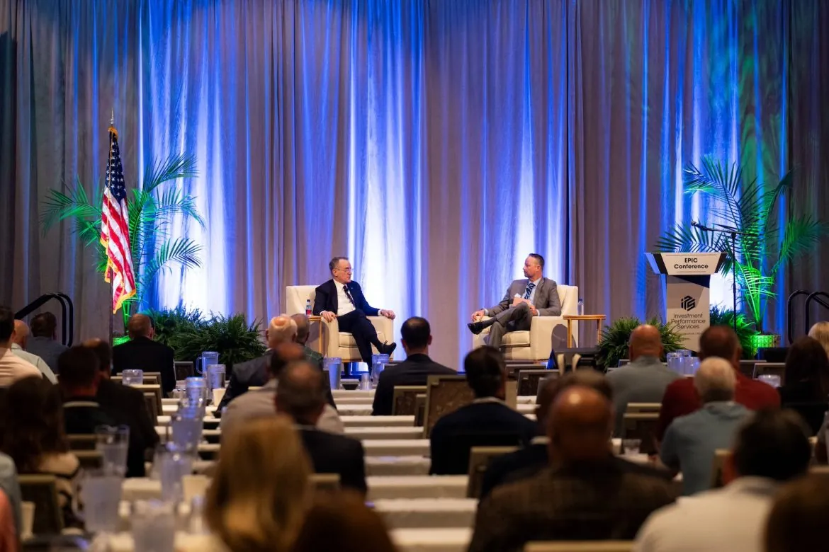 two men sitting on a stage at a conference